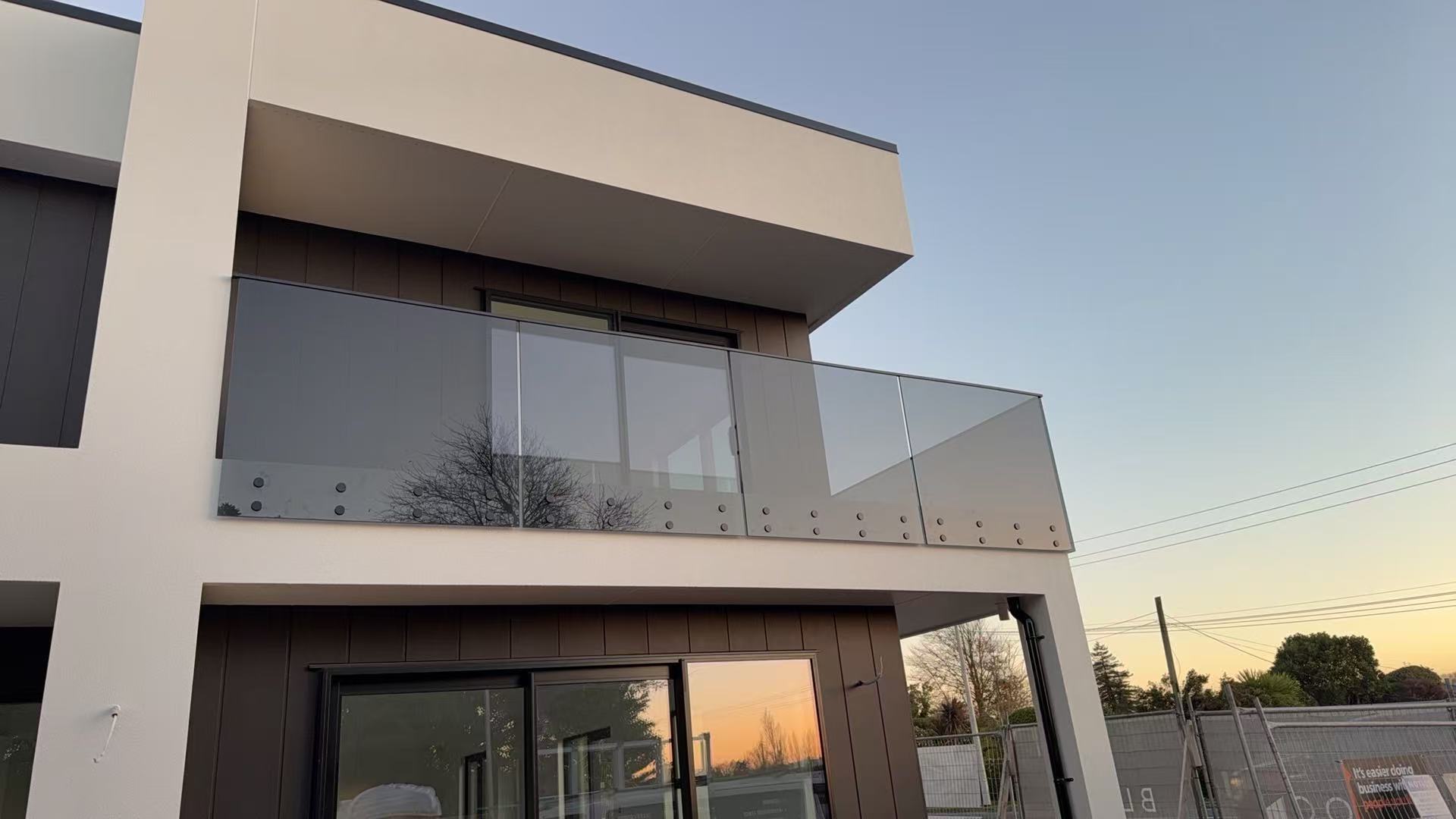 Frameless glass balustrade across a modern home's upper balcony