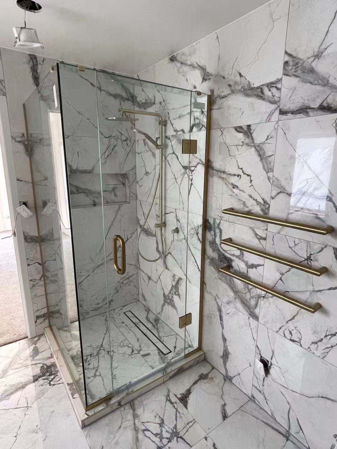 Frameless shower enclosure with brushed-gold hinges and handle